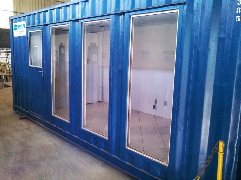Corredor interno de escritório em container com piso claro e iluminação no teto